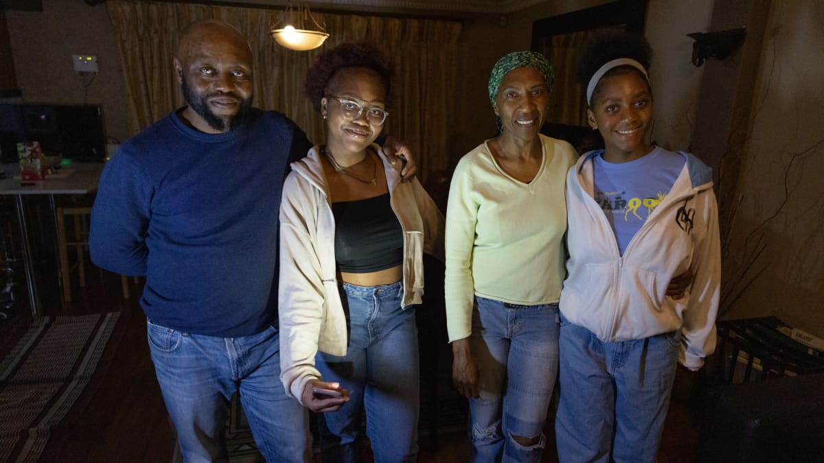 Eteläafrikkalainen perhe, isä, kaksi tytärtä ja äiti hämärässä olohuoneessa sähkökatkon aikana. 