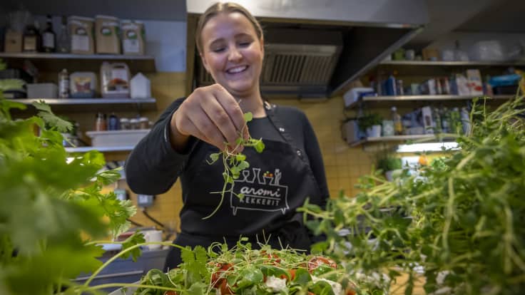 Nainen tiputtaa herneen versoja salaatin päälle.