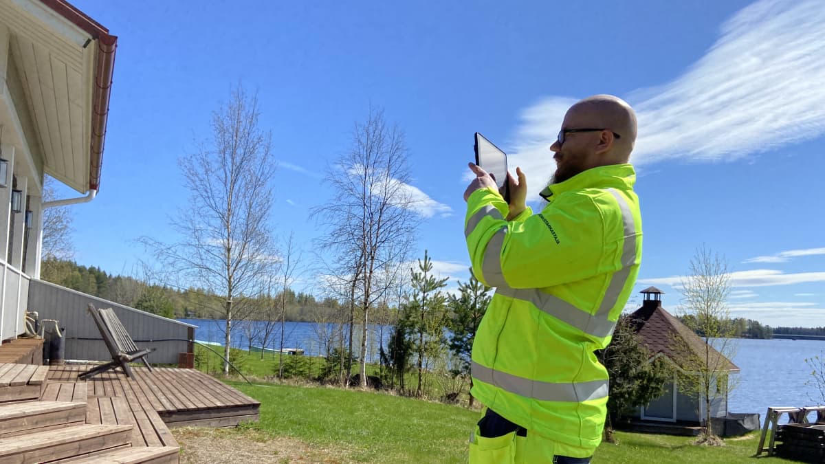 Mänttä-Vilppulan rakennustarkastaja Santtu Markkula on kirkkaan keltaisessa huomioasussa kuvaamasas tablettitietokoneella kiinteistöjä tarkastuskäynnilllään