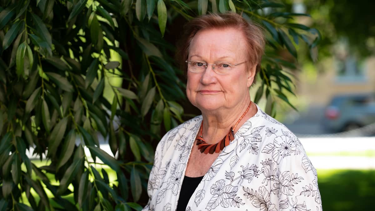 Tarja Halonen seisoo puistossa puun edessä.