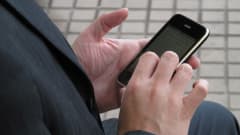 En anonym man som håller en mobil i händerna