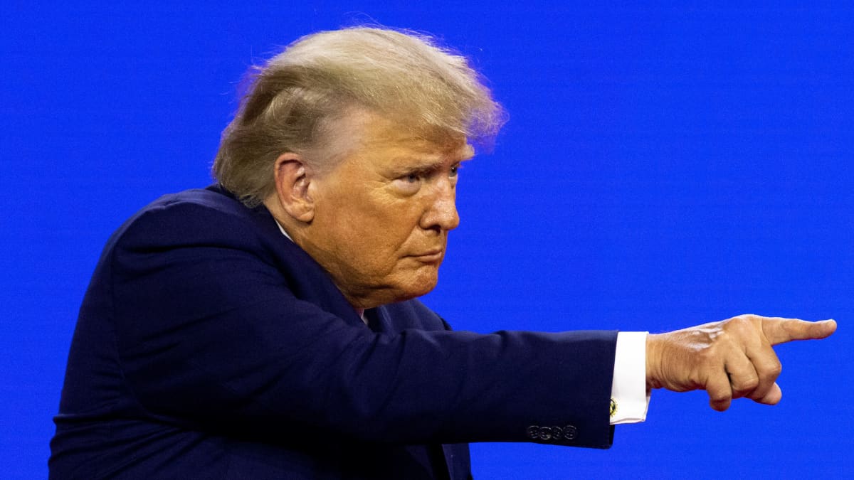 Donald Trump puvussa osoittaa jotakin sormellaan.