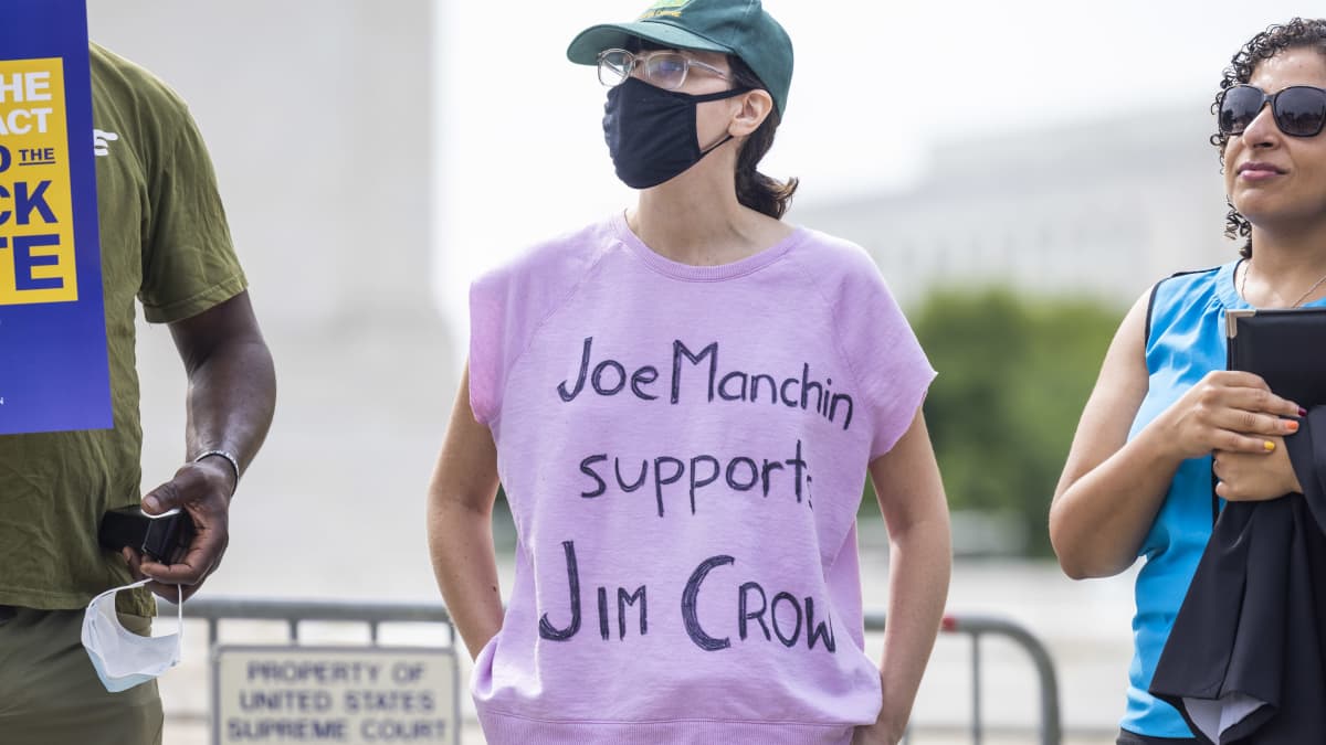 Nainen vaaleanpunaisessa paidassa mielenosoituksessa. Paidassa lukee "Joe Manchin supports Jim Crow."