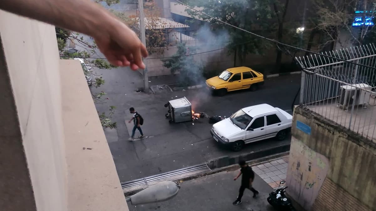 Kaadettu roskis on tulessa kadulla Teheranissa.