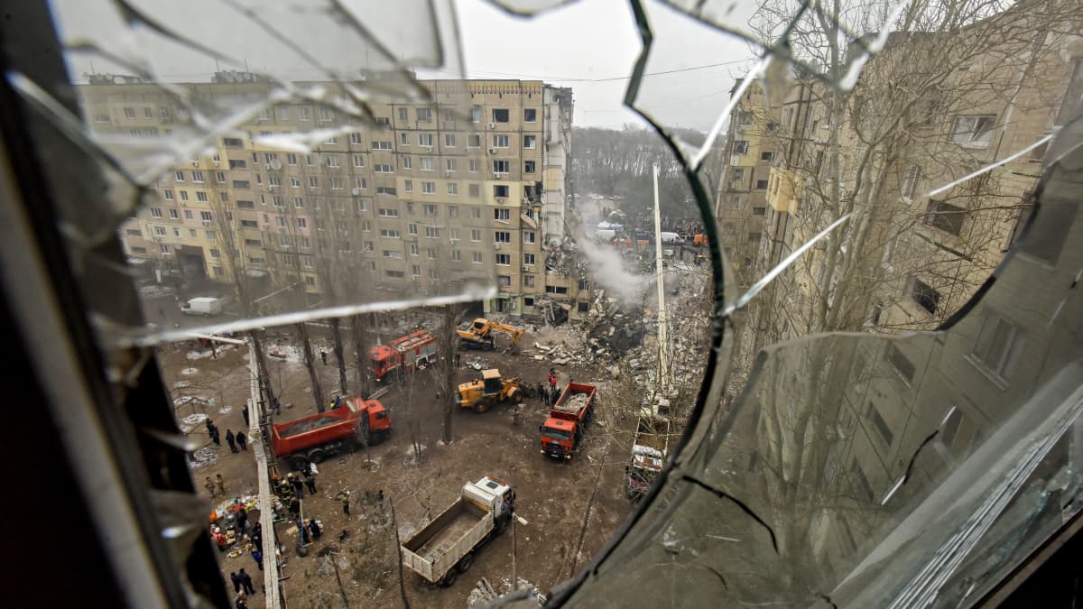 Näkymä rikkoutuneen ikkunan lasin läpi pihalle, jossa pelastustyöt jatkuvat Dniprossa, Kaakkois-Ukrainassa, 15. tammikuuta 2023.