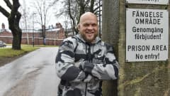 Immu Ilmen hymyilee iloisen vankilan portilla kirjoitettuaan kirjan vankien asenteista homoseksuaalisuuteen.