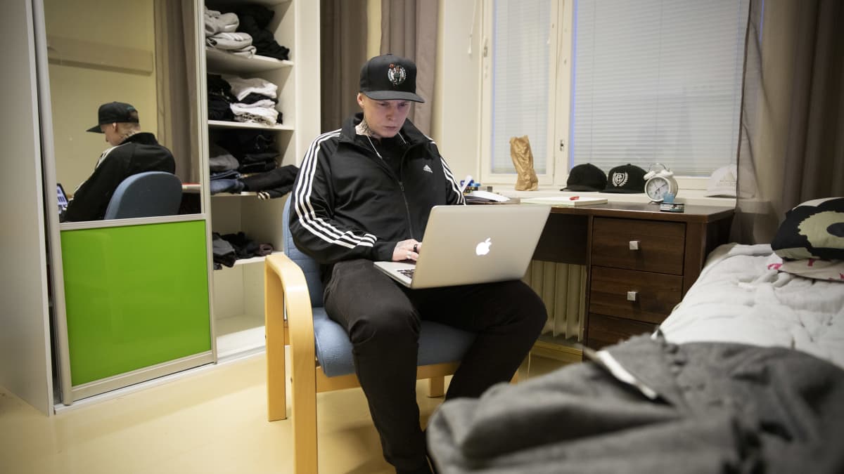 Patrik Lindblom istuu tuolilla ja käyttää läppäriä.