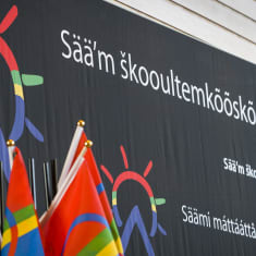 Saamelaisalueen koulutuskeskuksen logo ja saamenlippu