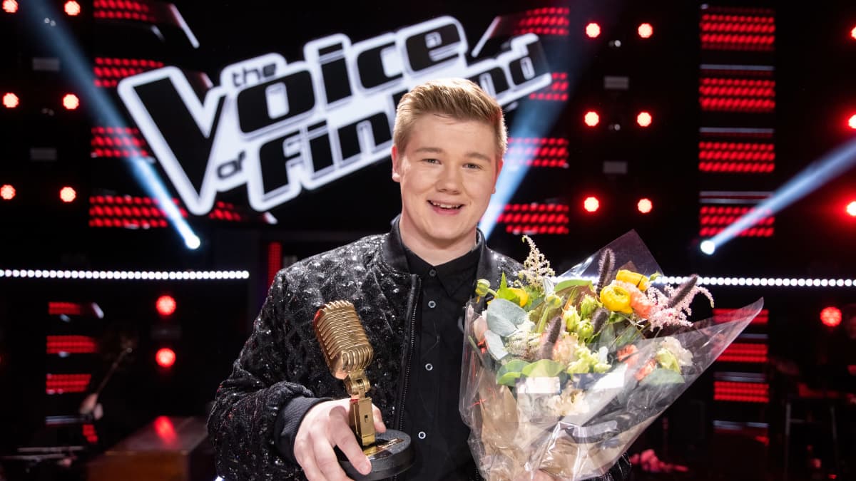 The Voice of Finland -kilpailun voittaja 2023, alajärveläinen Onni Kivipelto seisoo kukkakimppu ja mikrofoni kädessään.