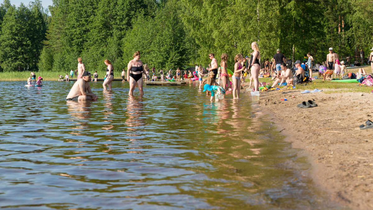 Paljon ihmisiä Tuomiojärven uimarannalla aurinkoisena kesäpäivänä.