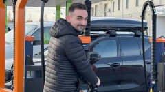 Mustaan toppatakkiin pukeutunut Niklas Keski-Kasari seisoo sähköauton latauspisteellä ja katsoo kameraan.