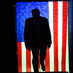 Donald trumpin siluetti Yhdysvaltain lipun edessä.
