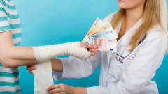En kvinnlig doktor tar emot pengar för att sköta en patient.