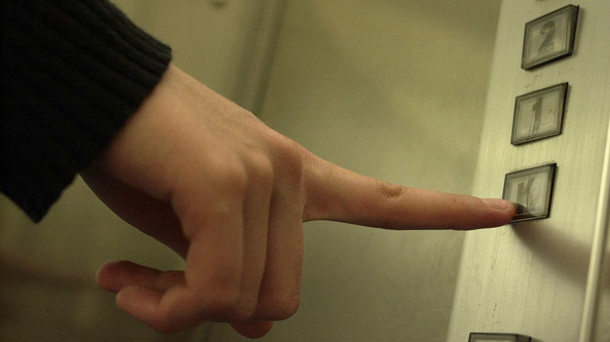 Finger trycker på en hissknapp.