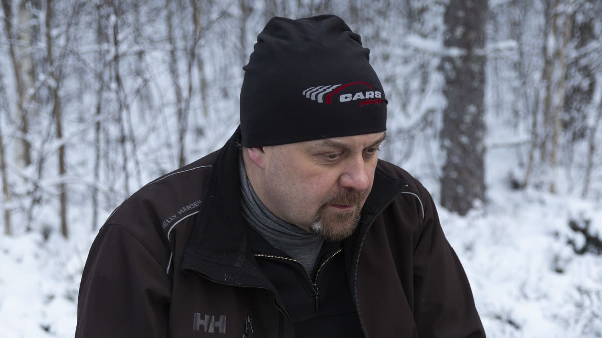Mika Kellokoski istuu penkillä lumisessa metsässä. 