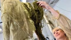 Tekstiili- ja vaatesuunnittelija Krista Virtanen ripustaa narulle punasipulin kuoriuutteella värjättyjä vihreitä lankoja.
