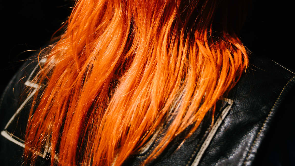 Alman pitkät oranssinpunaiset hiukset auringonvalossa.
