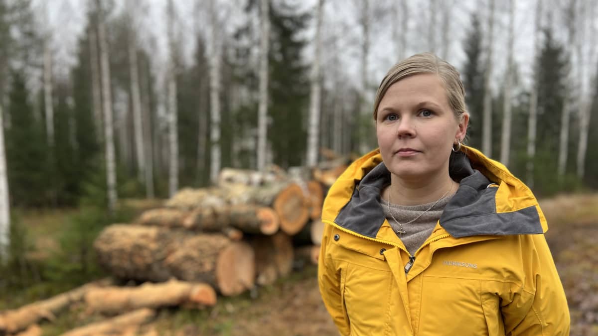 Diakoni Jonna Lemmetyinen polttopuurankojen edessä.