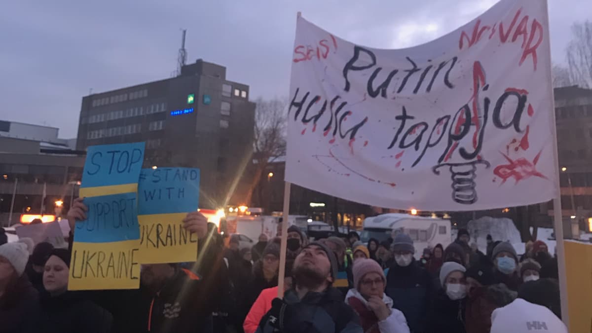 Mielenilmaisijoita Kokkolan torilla. Kyltissä on Seis Putin, hullu tappaja -teksti.
