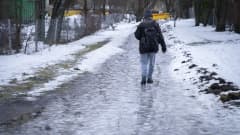 Mies kävelemässä jäätyneellä kevyenliikenteen väylällä Pohjois-Haagassa.