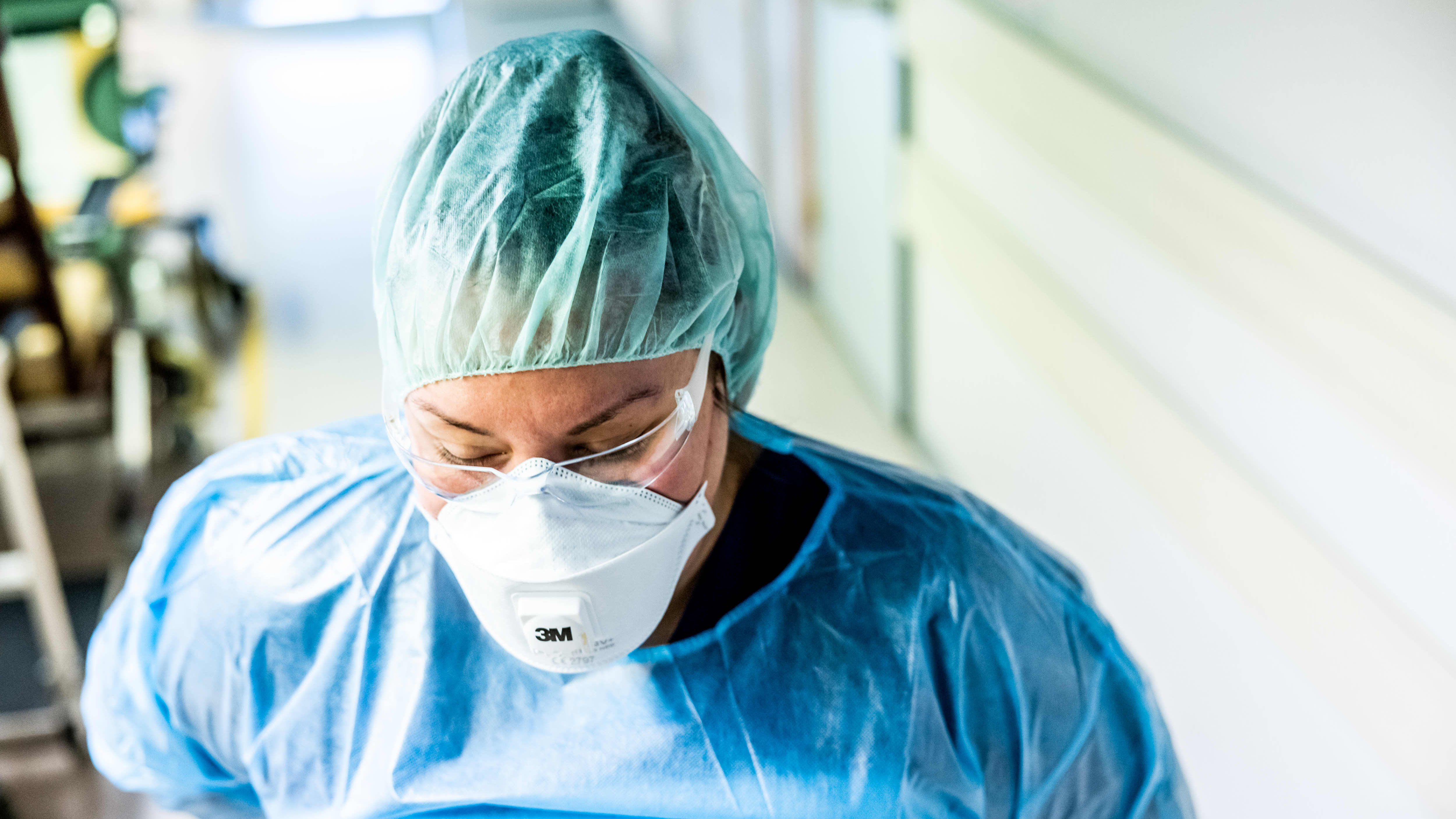 Sairaanhoitaja pukeutuu suojavarusteisiin koronaosastolla.