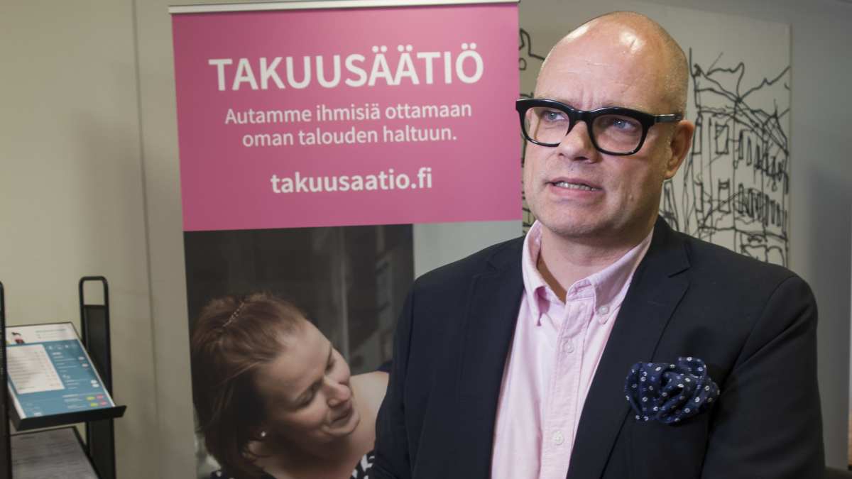 Takuusäätiön toimitusjohtaja Juha Panzar seisoo rollupin edessä Takuusäätiön toimistossa.