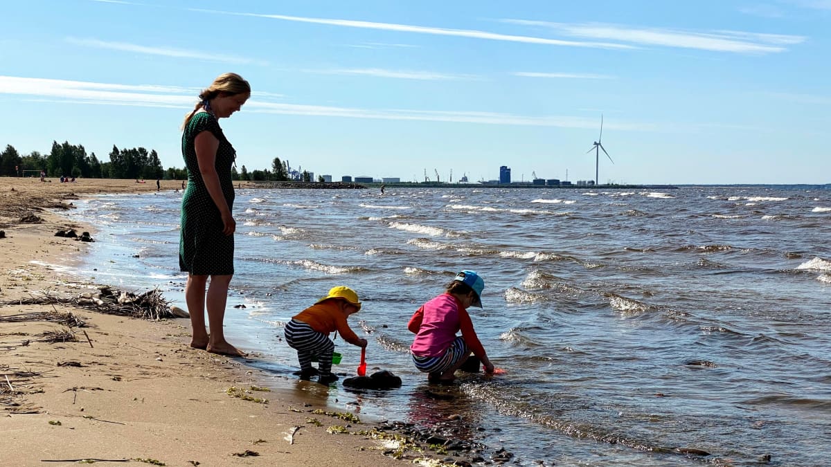 Lapsia leikkimässä rantavedessä aikuisen valvoessa Oulun Nallikarissa.