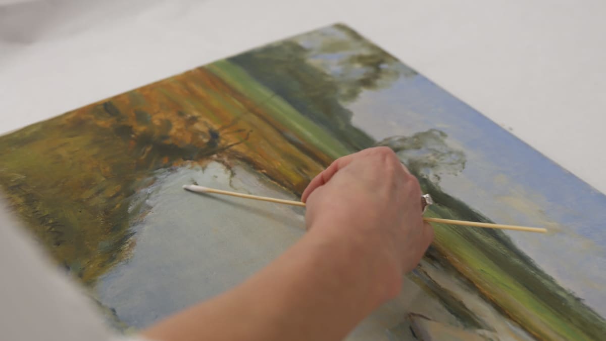 taidekonservaattori puhdistaa maalauksen pintaa