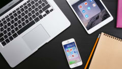 En iPhone, iPad och Macbook på ett bord.