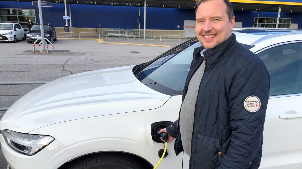 Ladattavan hybridin kuljettaja Jarno Kuustonen autonsa vieressä IKEAN latauspisteellä.