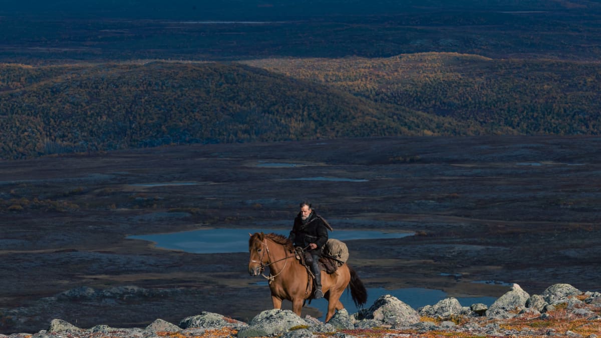 En ensam man till häst i ett öppet landskap i norra Finland.