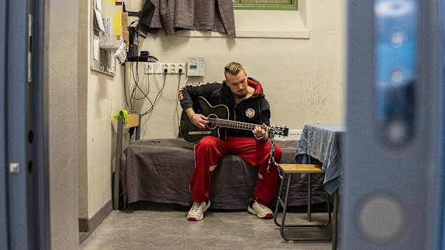 Vanki Tino Brunfeldt soittaa kitaraa sellissä Kuopion vankilassa.