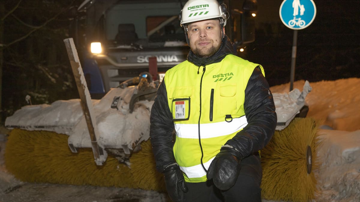Destian työmaapäällikkö Tuomas Rissanen seisoo harjalla varustetun kuorma-auton edessä. 