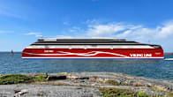 An artistic rendering of a red passenger ferry without a chimney at sea on a mostly sunny day, with a rocky coast seen in the foreground.