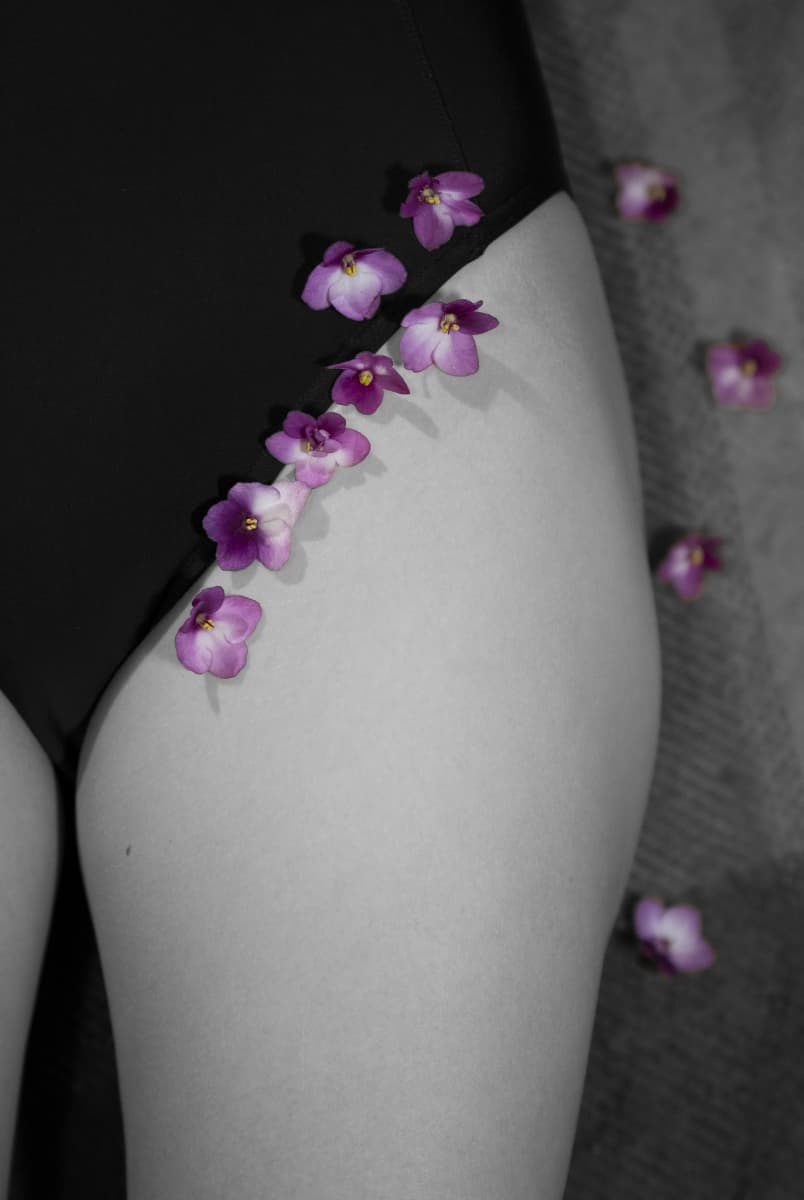 Bikinirajalle asetettuja purppuran värisiä kukkia muuten mustavalkokuvassa.