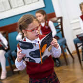 Virolainen koulutyttö tutkii kirjaa.
