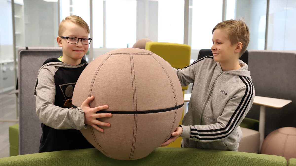 Nico Varis ja Eetu Kinnunen nostavat pallojakkaraa avoimessa opiskelutilassa.
