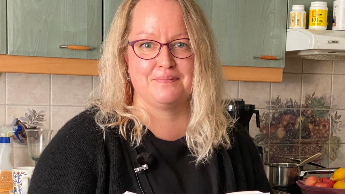 Tietokirjailija Jonna Pulkkinen keittiössä käsissään tuore teos Punainen pusero.