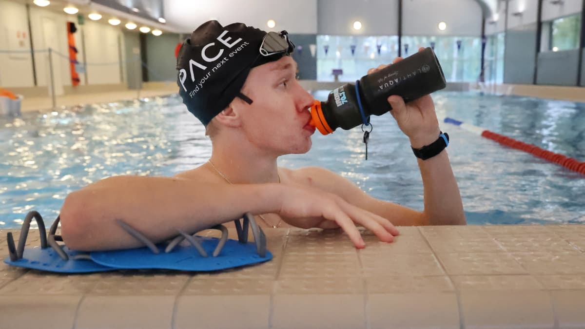 Triathlonisti Juuso Honkanen juo uima-altaan reunalla.