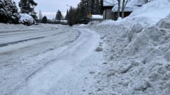 Tien pätkä, missä lunta kasautunut aurauksen myötä runsaasti jalkakäytävän reunaan sekä tielle.