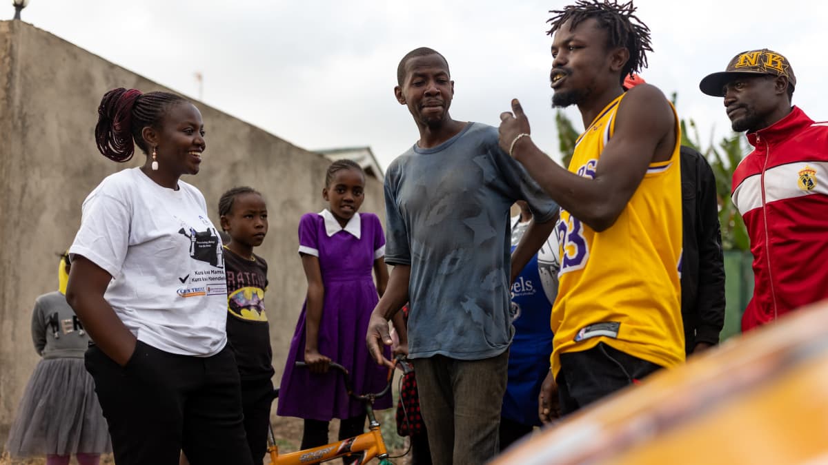 Nuori afrikkalainen vaaliehdokas (nainen) juttelee äänestäjiensä kanssa kadulla. 
