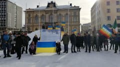 Mielenosoittajia Hämeenlinnan torilla Ukrainan liput käsissä.