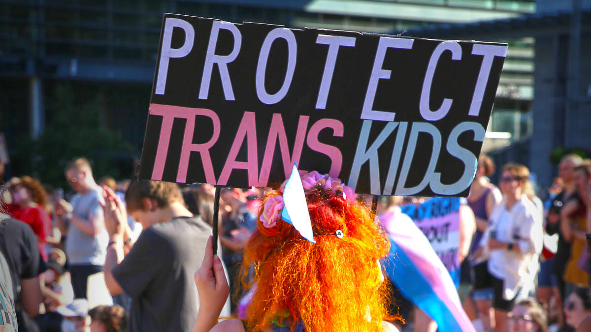Mielenosoittajanainen kantaa protect transkids -kylttiä.