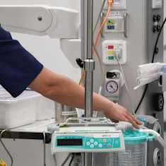 Kaksi terveydenhuollon ammattilaista säätää sairaalalaitteita.