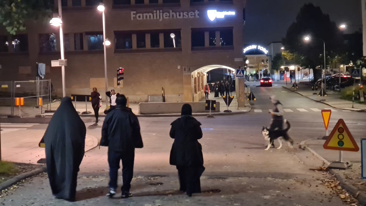 kaksi naista ja yksi mies kävelevät pimeässä poispäin kamerasta