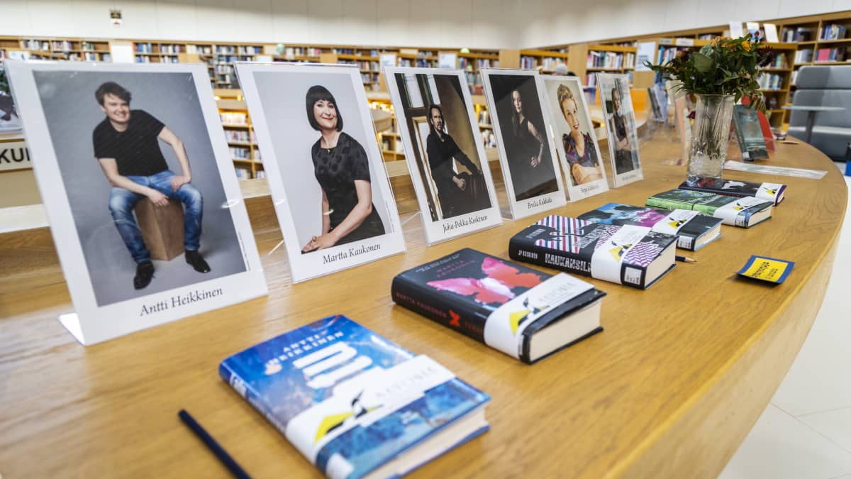 Savonia kirjallisuuspalkinnon ehdokas kirjoja ja kirjoittajien valokuvat Kuopion pääkirjaston pöydällä.