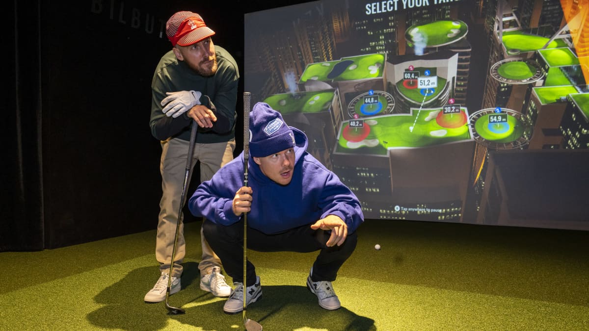 Rap-duo JVG:n Jare Joakim Brand ja Ville-Petteri Galle poseeraavat Salmisaari Golfin Golfsimulaattorissa.