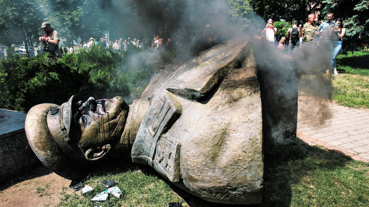 Marsalkka Zhukovin patsas on kaadettuna maassa. Taustalla näkyy mielenosoittajia. Jokin savuaa.