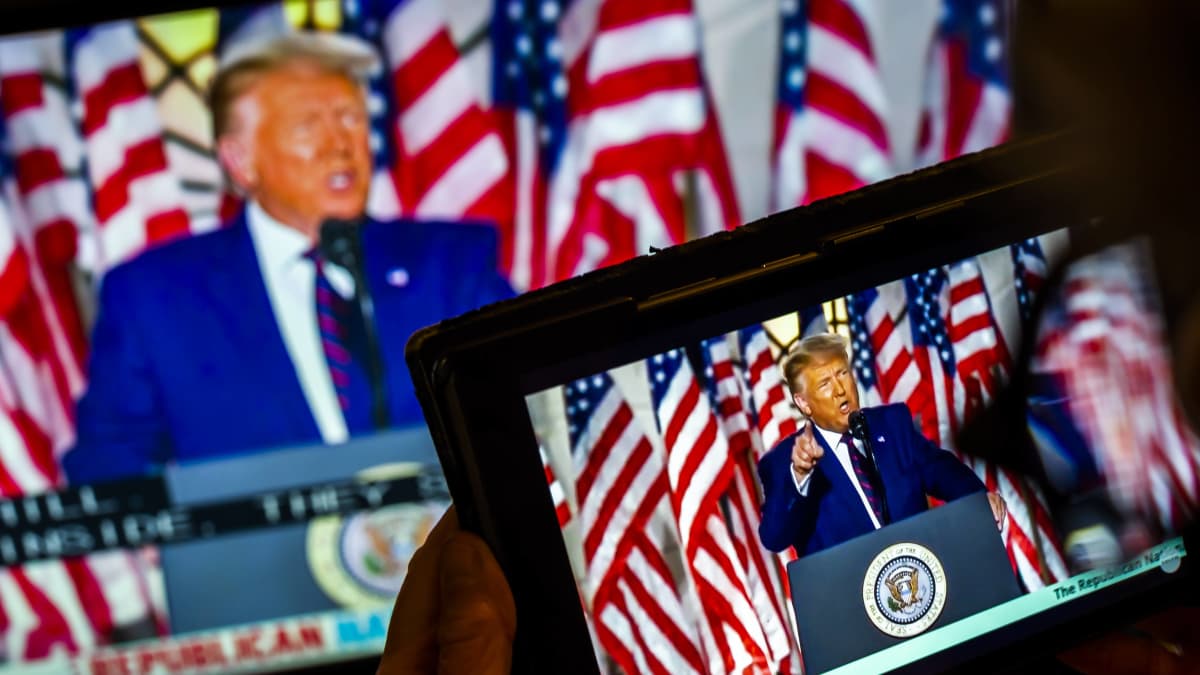 Donald Trump näkyy tabletin näytöllä kun hän puhuu republikaanien puoluekokouksessa. Kuvassa Trump näkyy myös isommalla näytöllä kuvan takaosassa. 