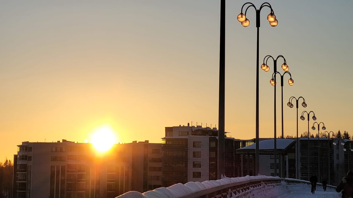 Auringonnousu valaisee katulamput Jyväskylässä Kuokkalan sillalla talvella.